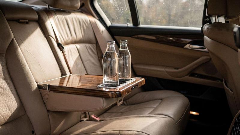 Rear passenger cabin of a chauffeur sedan with folded tray table and water bottles